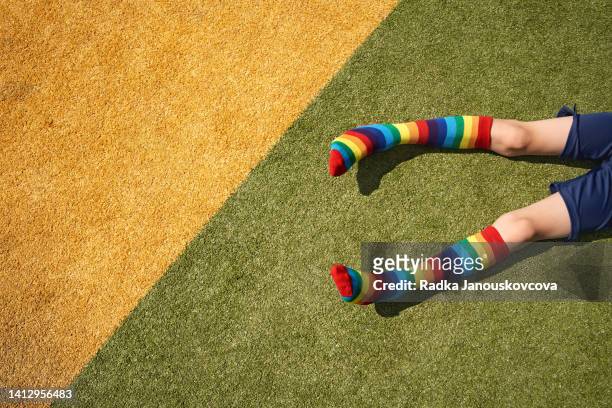 legs of a child with rainbow socks on green and yellow background. lgbt support concept. - human rights of children stock-fotos und bilder
