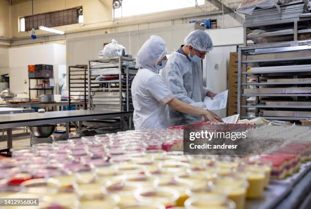 engineer working at a food processing plant and doing quality control on some desserts - food processing plant stockfoto's en -beelden