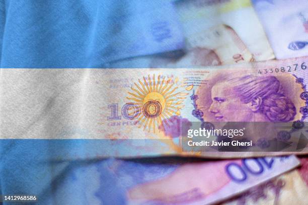 argentine pesos in cash and argentina flag - eva perón stock pictures, royalty-free photos & images