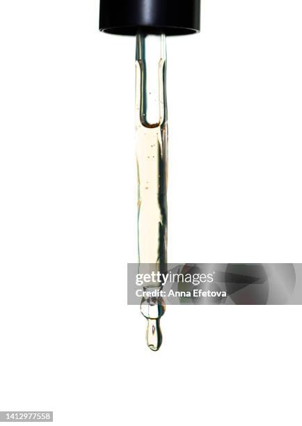 drop of essential oil is dripping from glass pipette on white background. concept of beauty procedures and body care. polyglutamic acid is a new hyaluronic acid. macro photography - huile de massage photos et images de collection