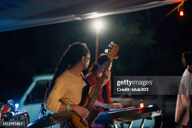 mid adult man playing a bass guitar in a band at an outdoor music festival - jazz music photos 個照片及圖片檔