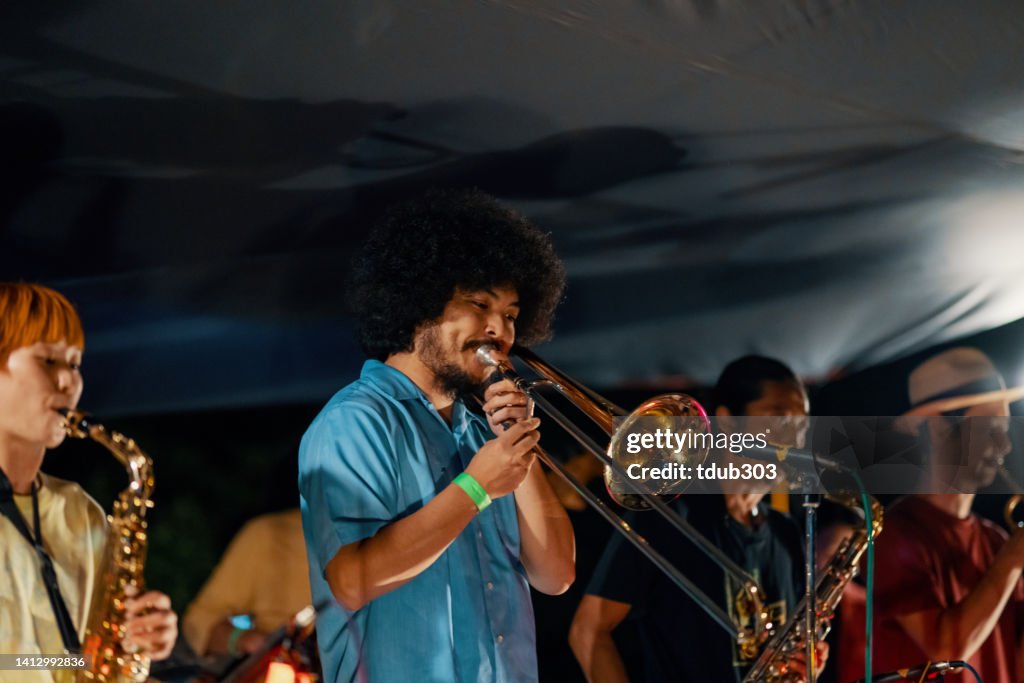Trombonist playing a trombone at an outdoor music festival