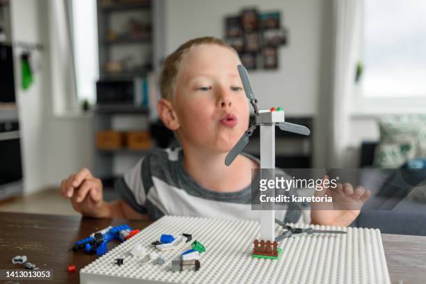 boy blowing on invented by him wind turbine - estonia school stock pictures, royalty-free photos & images