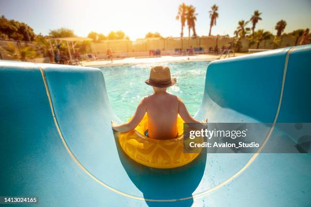 boy on vacation playing in the waterslide in the inflatable ring - water slide stockfoto's en -beelden