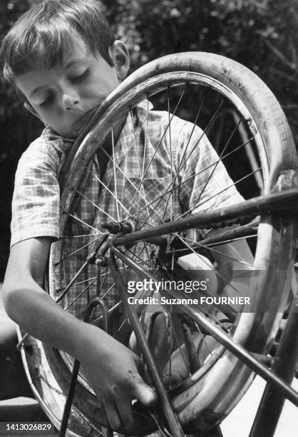 Enfant réparant la roue de son vélo, dans les années 1970.