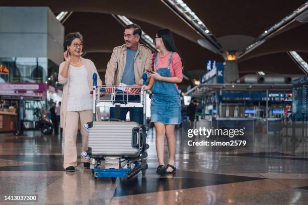 abuelos asiáticos sonrientes con nietas que viajan juntas en vacaciones - departure board front on fotografías e imágenes de stock