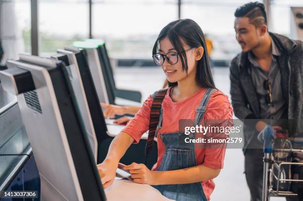 junge asiatische reisende, die den check-in-automaten am flughafen benutzt und die bordkarte erhält. individuelles geschäftsreisekonzept. - counter stand stock-fotos und bilder