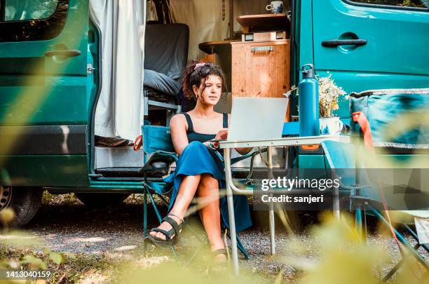 woman working on laptop camping in a van - camper van imagens e fotografias de stock