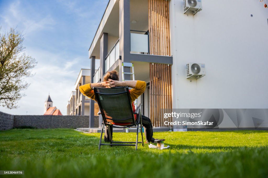 Homme fatigué se reposant sur une chaise longue dans la cour tout en prenant une pause de la coloration