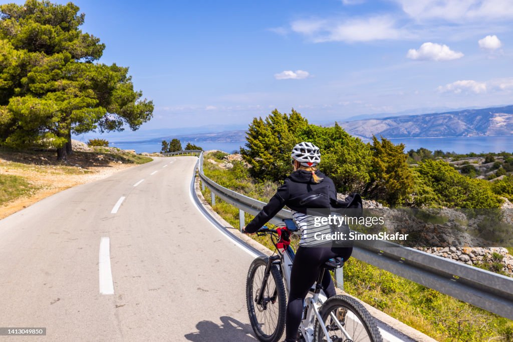 Female cyclist rides bike on mountain road