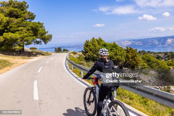 female cyclist rides bike on mountain road - regio-dalmatië-kroatië stockfoto's en -beelden