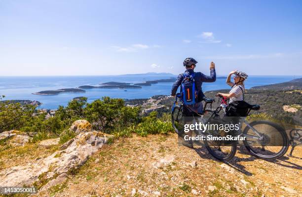 male and female biker with bicycles giving high five while standing on top of mountain - regio-dalmatië-kroatië stockfoto's en -beelden