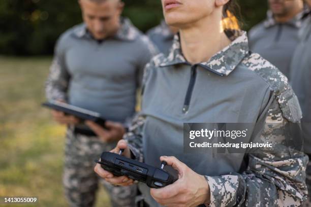 frau aus dem militärteam, die die drohne fährt, während sie eine drohnenfernbedienung benutzt - militär stock-fotos und bilder