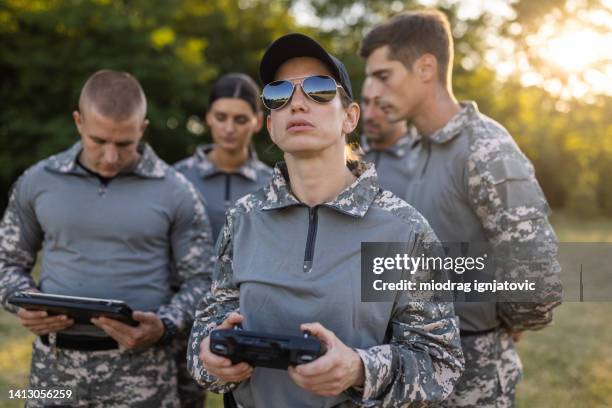 woman from the military team, driving the drone while using drone remote control - drone pilot stock pictures, royalty-free photos & images