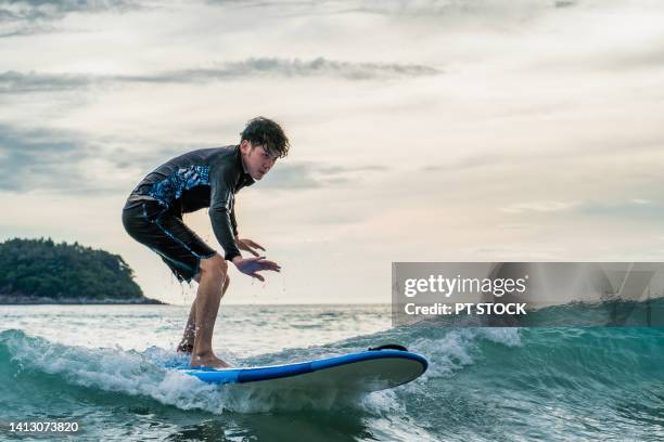 a man in a bathing suit is surfing in the sea - asian surfer stockfoto's en -beelden