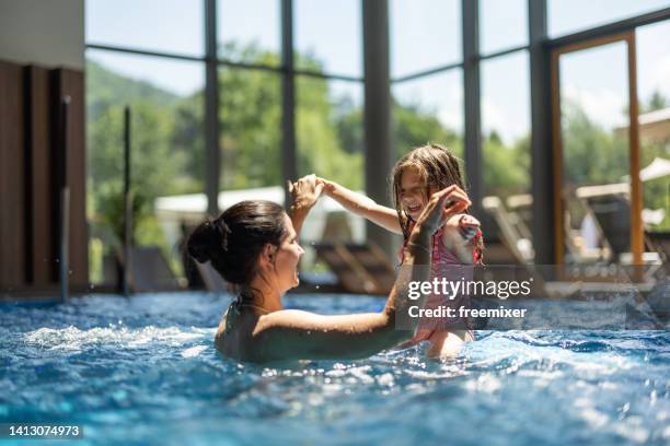 mother and daughter having fun in swimming pool - family holidays hotel stockfoto's en -beelden