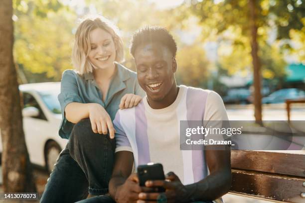 multiracial couple having video call on smart phone and laughing - friends laughing at iphone video stock pictures, royalty-free photos & images