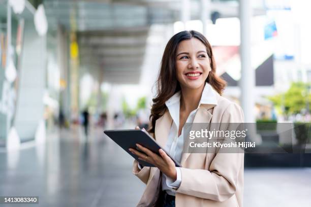 asian businesswoman using a digital tablet working in the city - versicherungsvertreter stock-fotos und bilder
