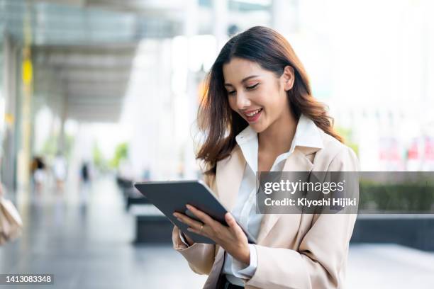 asian businesswoman using a digital tablet working in the city - vragenlijst stockfoto's en -beelden