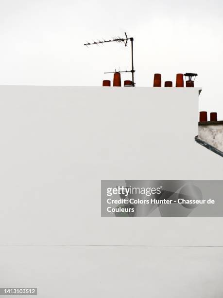 white painted concrete wall with terracotta chimneys and rake antenna in paris, france - dachgiebel stock-fotos und bilder
