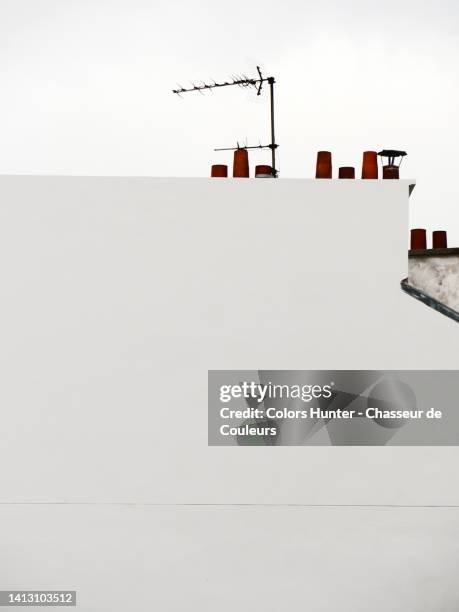 white painted concrete wall with terracotta chimneys and rake antenna in paris, france - empena - fotografias e filmes do acervo