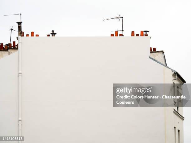 angled white concrete wall with windows, terracotta chimneys and rake antenna in paris, france - paris city stock pictures, royalty-free photos & images