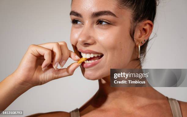 attractive young adult woman taking vitamin - comprimido imagens e fotografias de stock