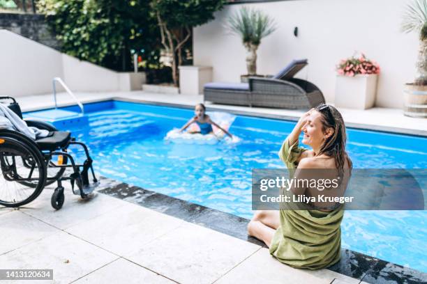 disabled woman without legs sitting on the side of the pool. - amputado imagens e fotografias de stock