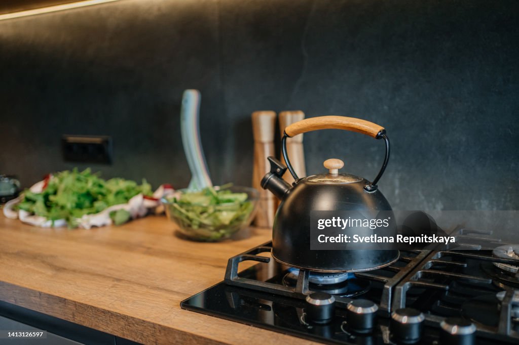Kettle is on the gas stove, green salad on the table, homemade dinner in the kitchen