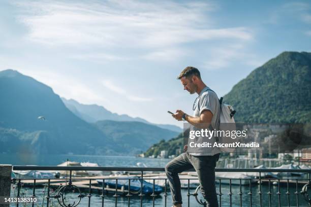 man uses mobile phone on lakeshore - men docking photos stock pictures, royalty-free photos & images
