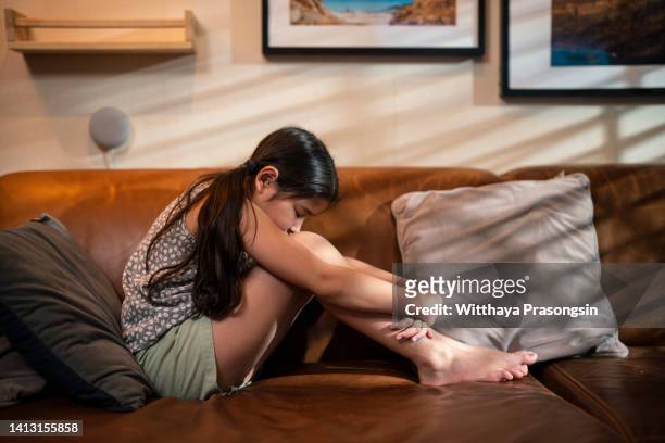 upset woman sitting on couch alone at home - drug rehab stockfoto's en -beelden