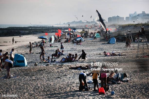 People spend a late afternoon at Rockaway Beach on August 5, 2022 in the Queens borough of New York City. Much of the East Coast, is expected to see...