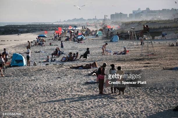 People spend a late afternoon at Rockaway Beach on August 5, 2022 in the Queens borough of New York City. Much of the East Coast, is expected to see...