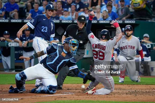 Alex Verdugo of the Boston Red Sox scores against Salvador Perez of the Kansas City Royals on a J.D. Martinez two-run double in the fourth inning at...
