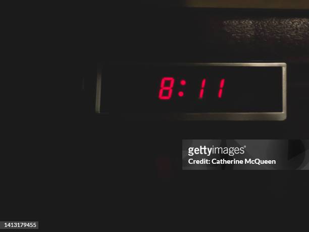 retro digital alarm clock in dark room in front of stack of books in the shadows - countdown digital photos et images de collection