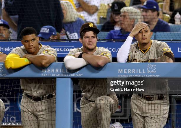 Juan Soto, Wil Myers and Manny Machado of the San Diego Padres watch from the dugout trailing 8-0 to the Los Angeles Dodgers during the fourth inning...