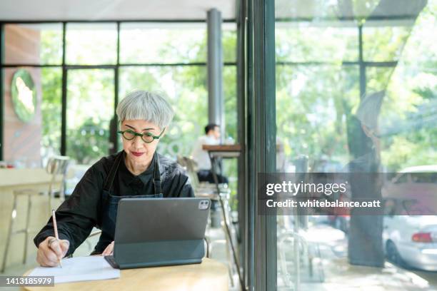 asian senior business owner calculating business performance. - royalty payment stock pictures, royalty-free photos & images