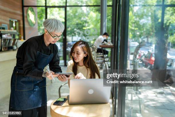 asian senior business owner is serving customers. - royalty payment stock pictures, royalty-free photos & images