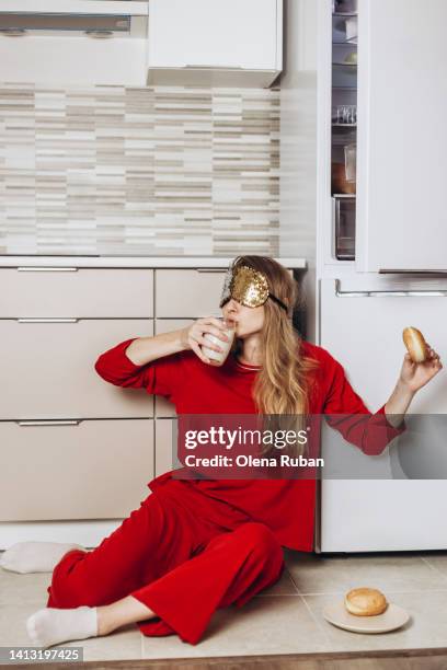 young woman in sleep mask having midnight snack in the kitchen. - milk concept stock pictures, royalty-free photos & images