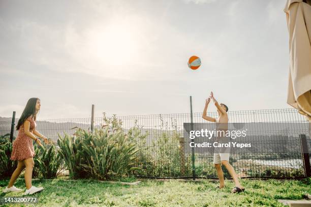 friends enjoying summer afternoon  playing beach ball in back yard. - beach volleyball friends stock pictures, royalty-free photos & images