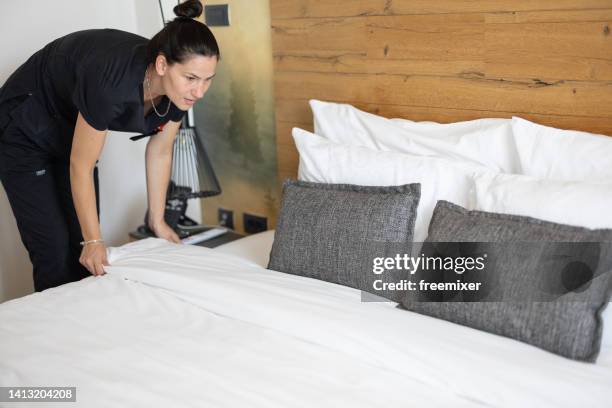 junges zimmermädchen in schwarzer uniform, das bett in der hotelsuite macht - neueröffnung stock-fotos und bilder