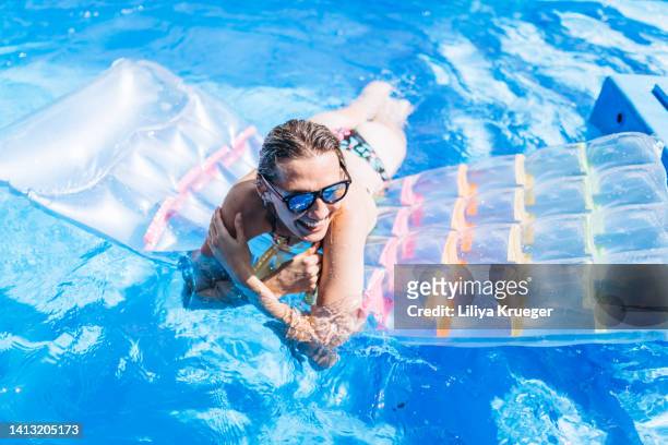 happy disabled woman swimming in the pool on a hot sunny day. - freibad stock-fotos und bilder