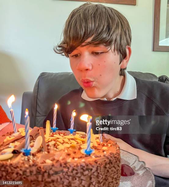 fourteen year old boy blowing out birthday candles - boys birthday stock pictures, royalty-free photos & images