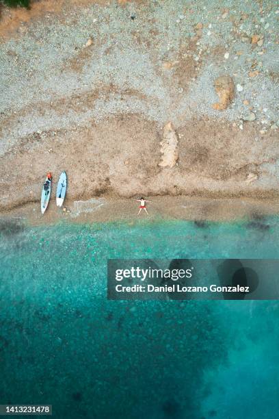 dead man remains on beach shore next to two paddle boards - coastal deprivation stock pictures, royalty-free photos & images