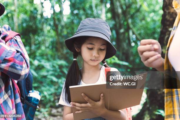 children write and drawing it in a notebook while hiking in the woods, knowledge outside the classroom, exploration, learning about the nature of children - very young thai girls stock pictures, royalty-free photos & images