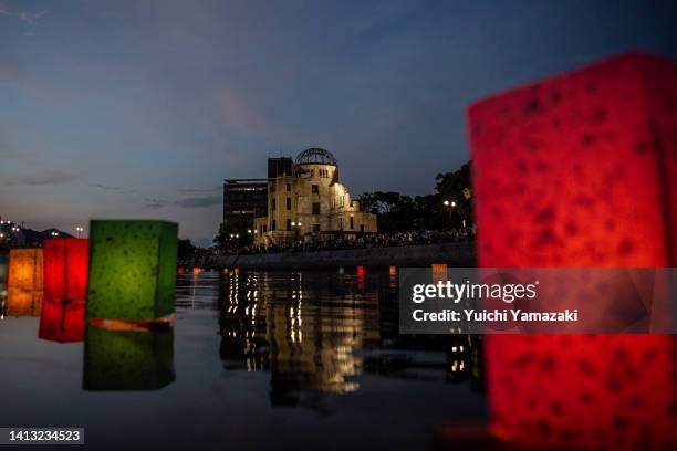Paper lanterns are floated on the Motoyasu river as The Atomic Bomb Dome looms in the background on August 06, 2022 in Hiroshima, Japan. Today marks...