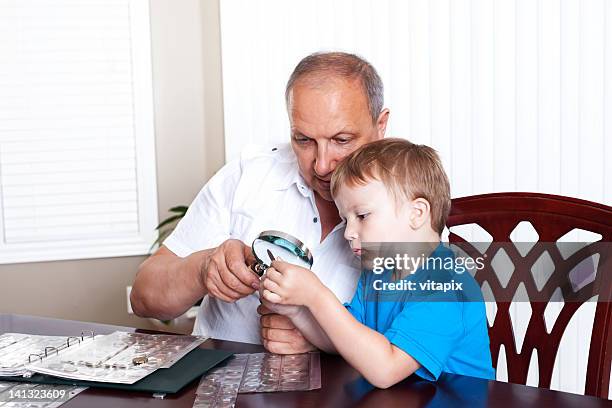 grandfather and grandson looking at coin collection. - coin collection stock pictures, royalty-free photos & images