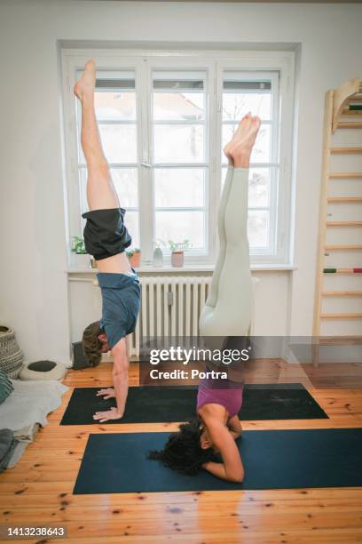 fit couple doing handstand yoga at home - upright position stock pictures, royalty-free photos & images