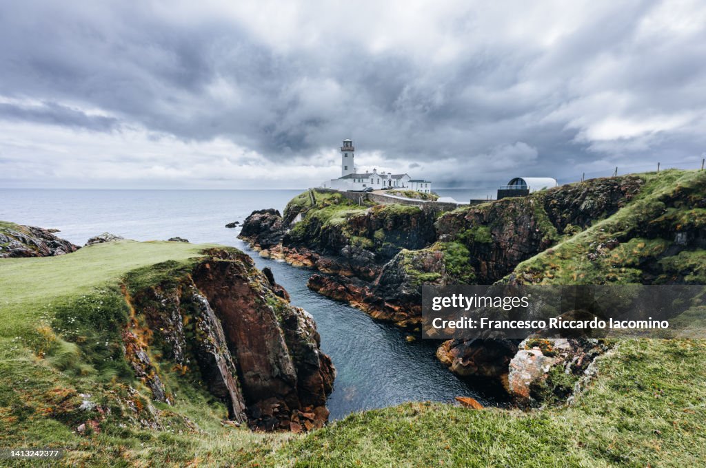 UK, Northern Ireland, County Antrim, Ballintoy, woman walking on the path to Carrick-a-Rede Rope Bridge,