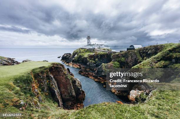 uk, northern ireland, county antrim, ballintoy, woman walking on the path to carrick-a-rede rope bridge, - northern ireland stock pictures, royalty-free photos & images